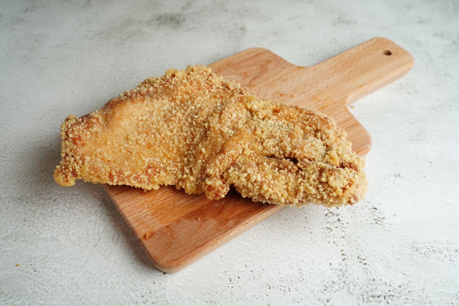 Golden breaded cutlet on a wooden cutting board