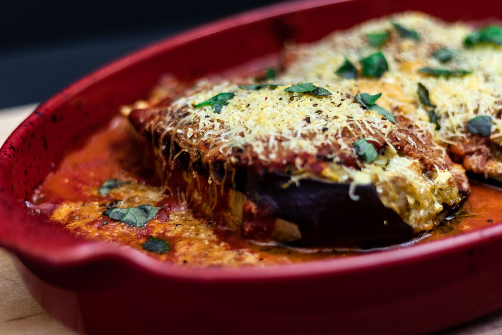 Baked eggplant Parmesan with bubbling cheese in a red dish