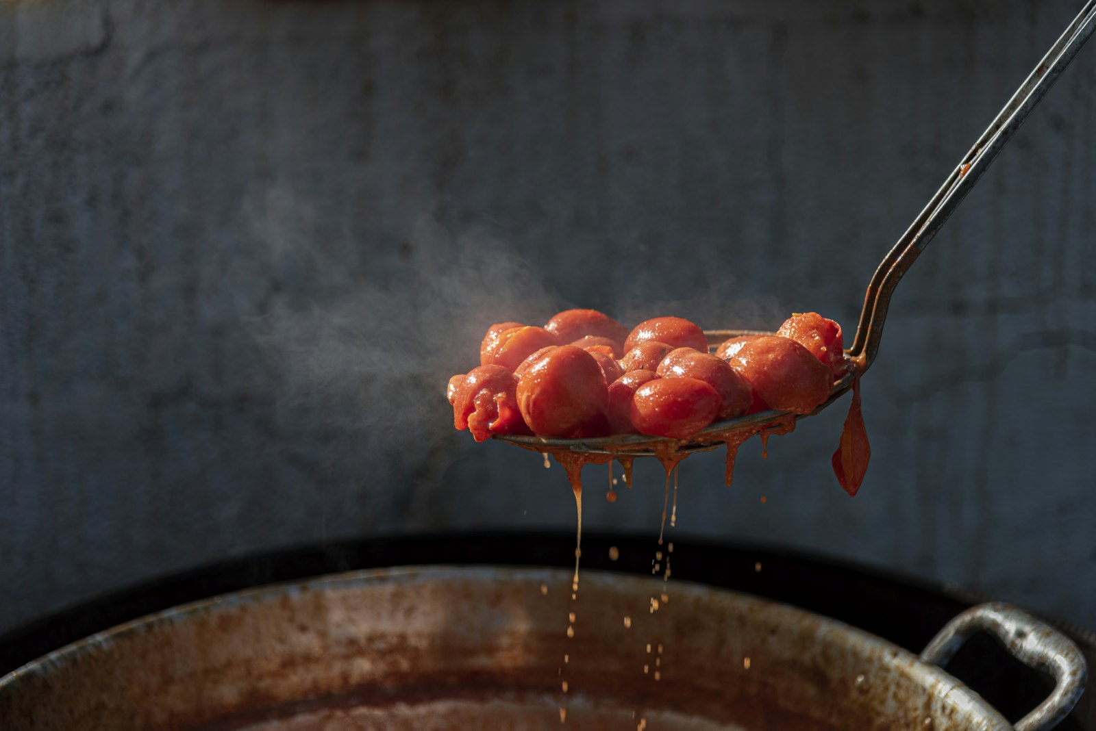 Ladle lifting tomatoes from a big pot of Sunday sauce
