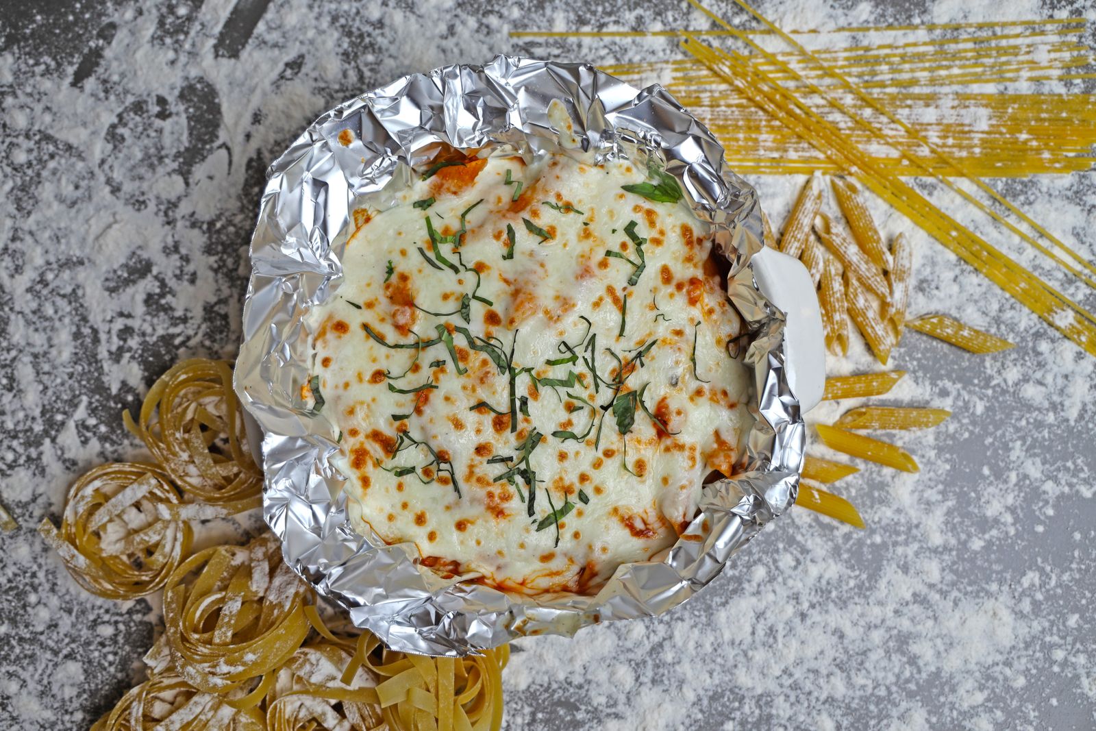 Baked pasta with cheese in a foil pan, ready for make-ahead Tetrazzini recipes