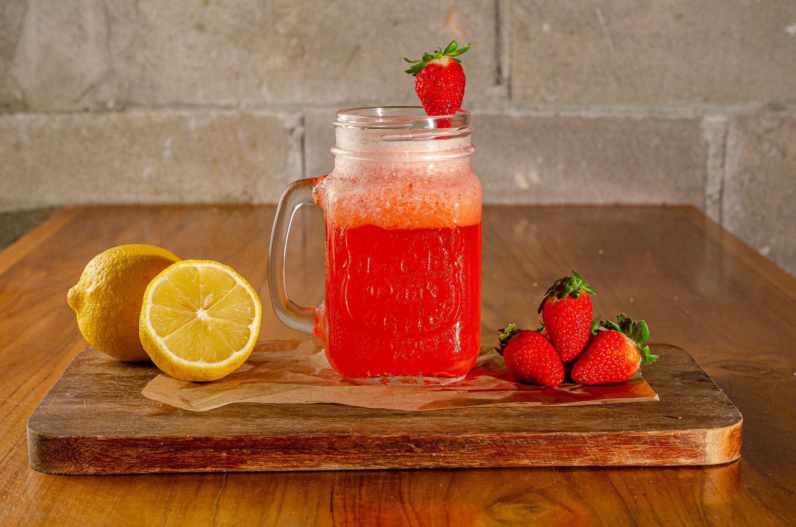 Pink strawberry lemonade punch in a jar with lemons and strawberries