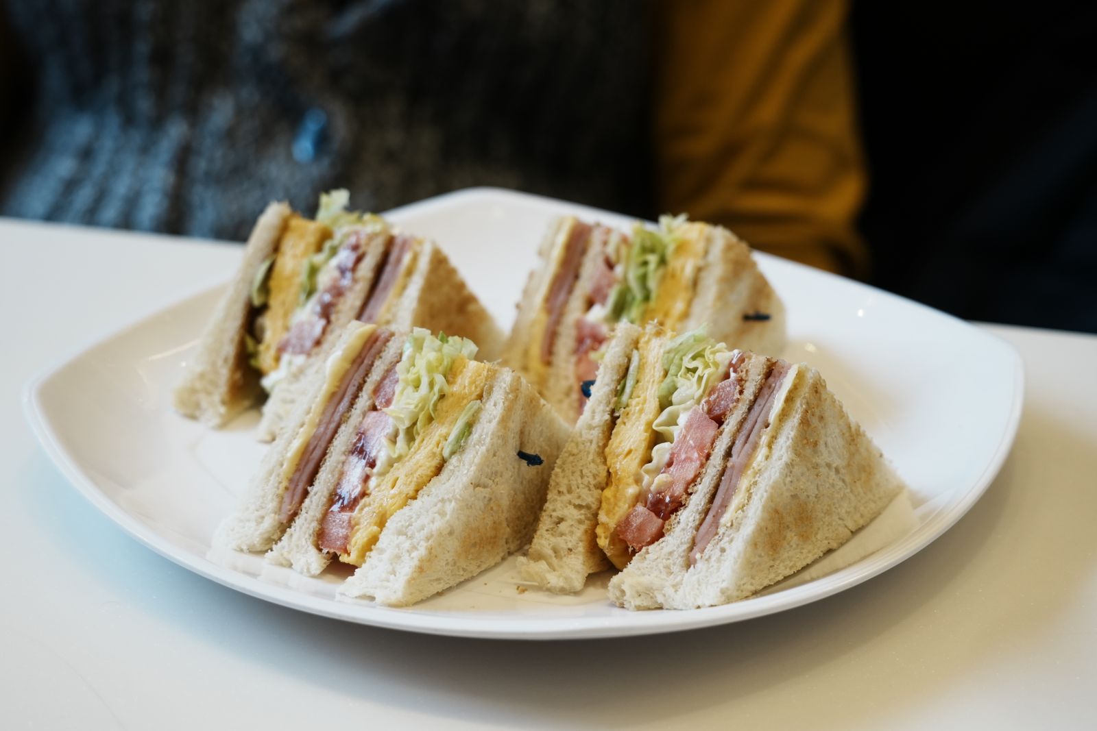 Stack of hearty layered sandwiches cut in triangles on a white plate