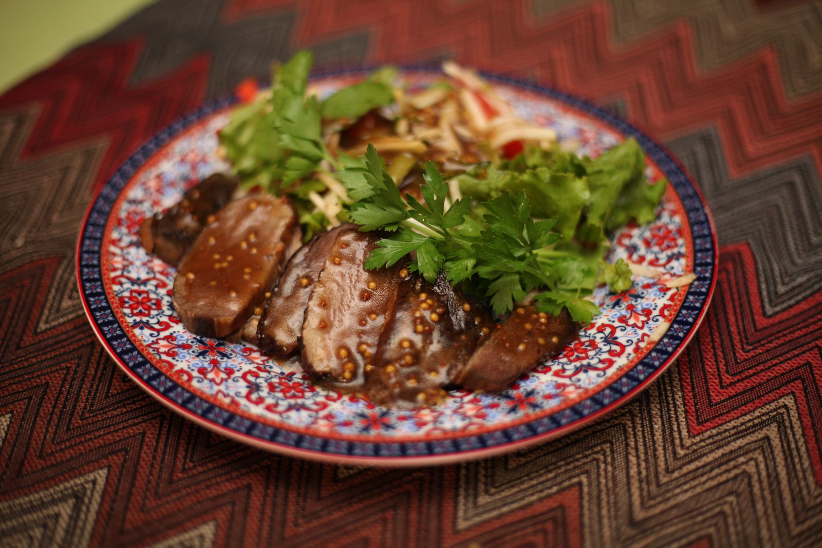 Sliced herb-crusted beef tenderloin on a patterned plate