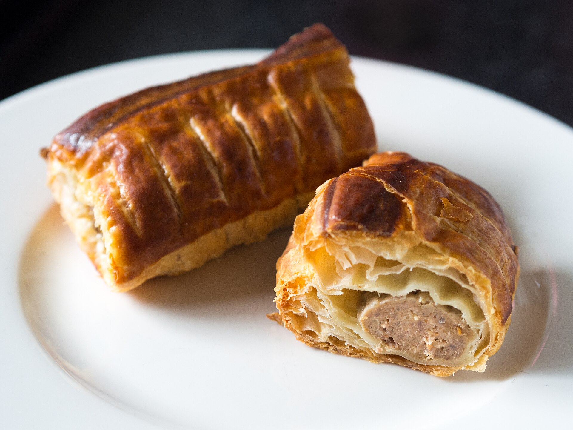 Flaky golden sausage roll cut open on a plate, classic British holiday party food