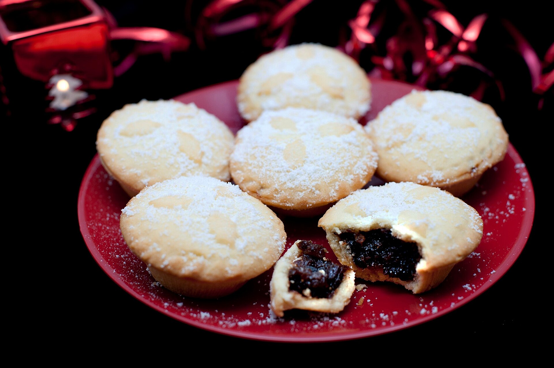 Mince pies dusted with powdered sugar on a red plate
