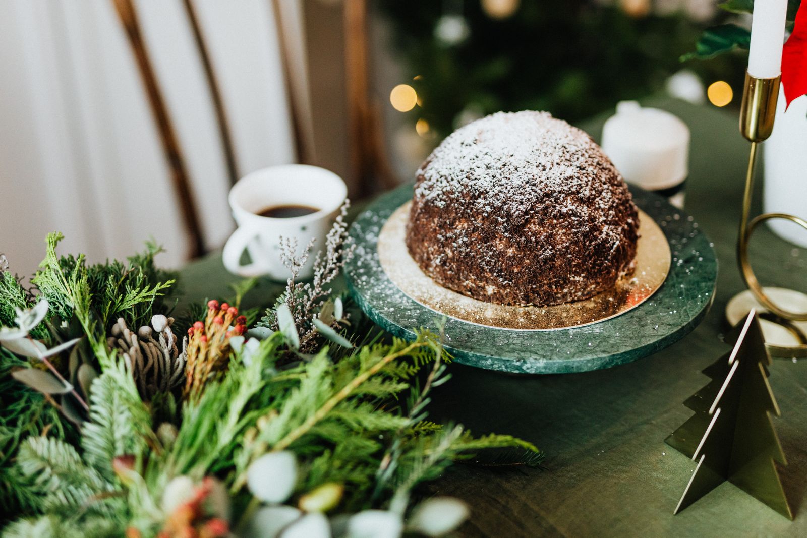 Dark steamed fruit pudding with holly on a festive table