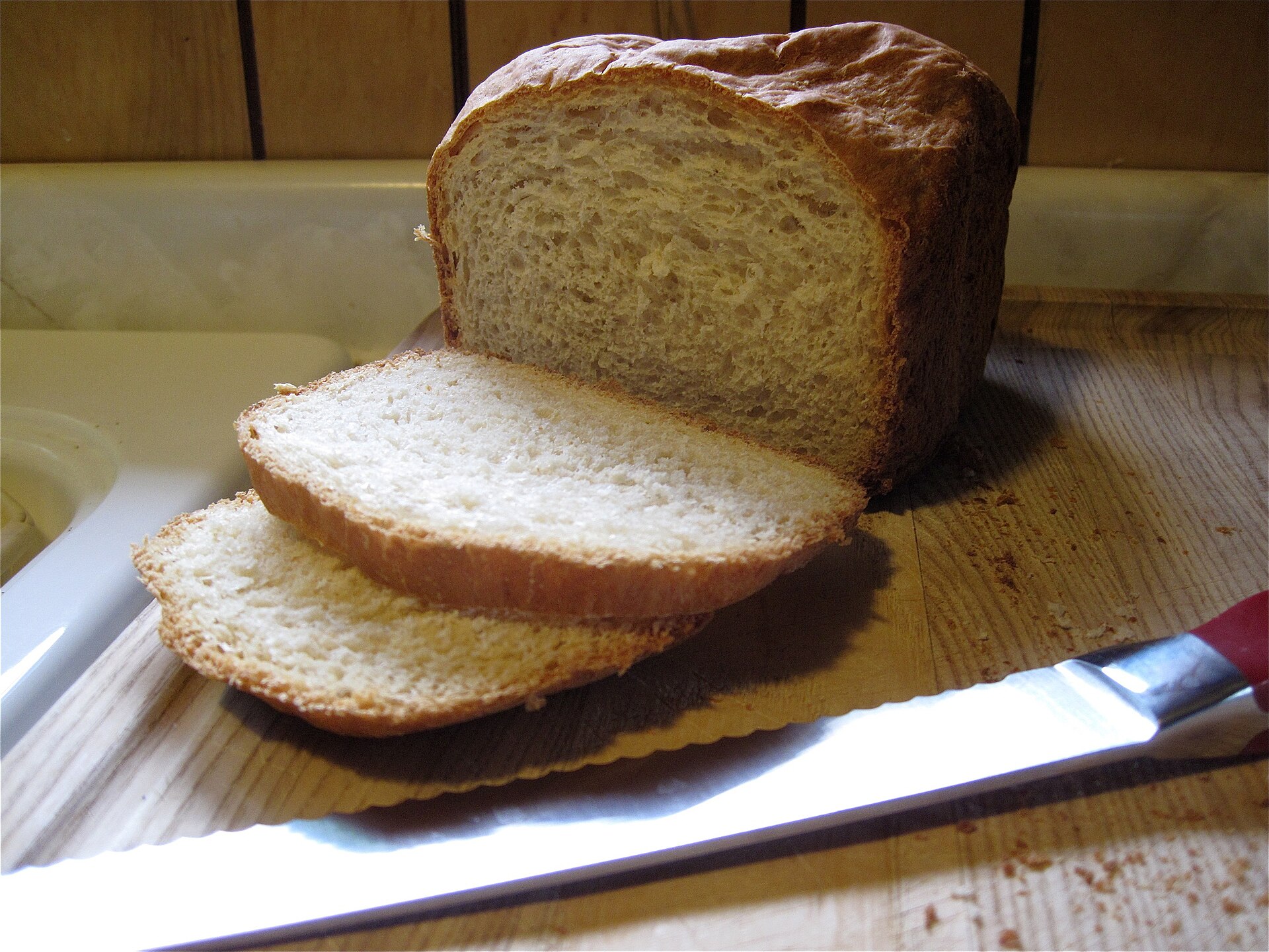 Homemade sandwich bread loaf with sliced pieces and a bread knife