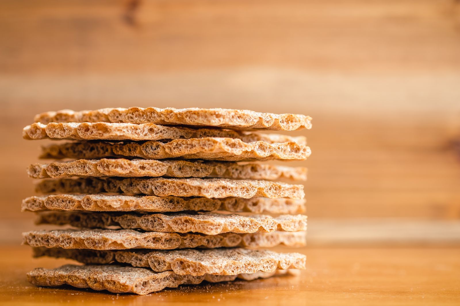 Stack of homemade whole wheat crackers on a wooden board
