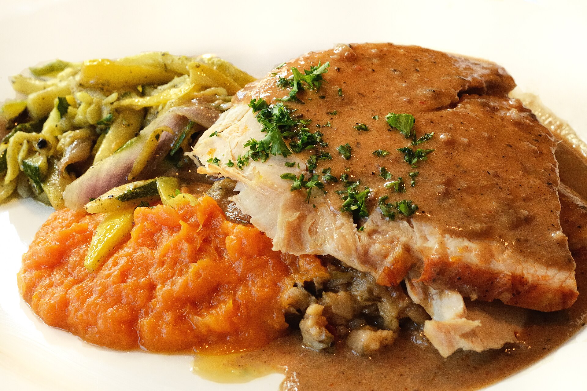 Sliced roast turkey with gravy and sweet potatoes, a plate of old fashioned Thanksgiving recipes