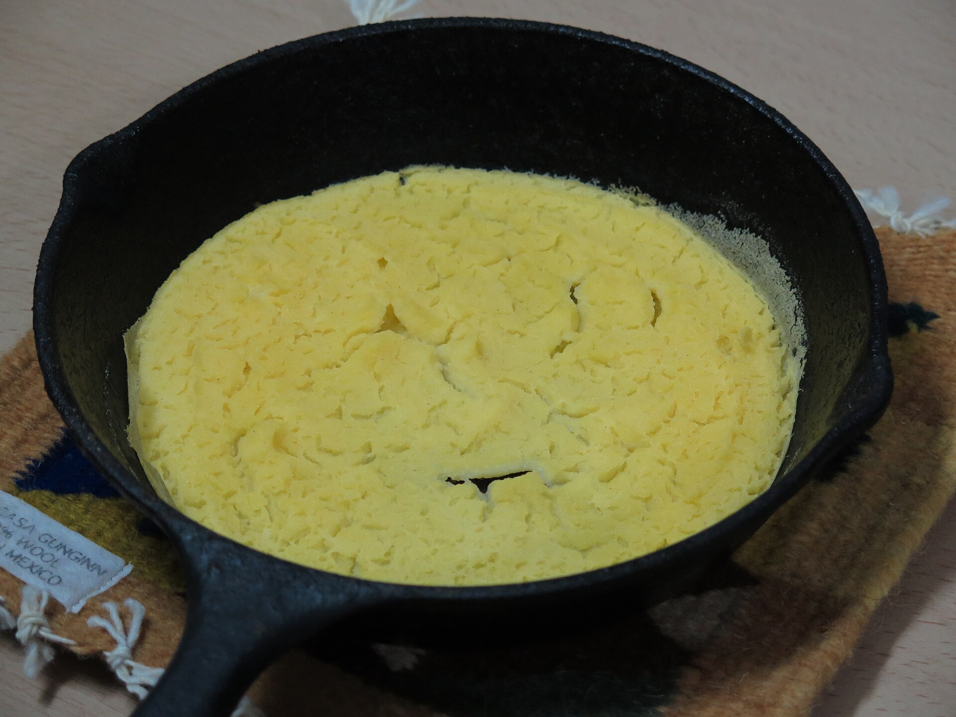 Golden cornmeal johnnycake in a cast iron skillet, from old fashioned Thanksgiving recipes