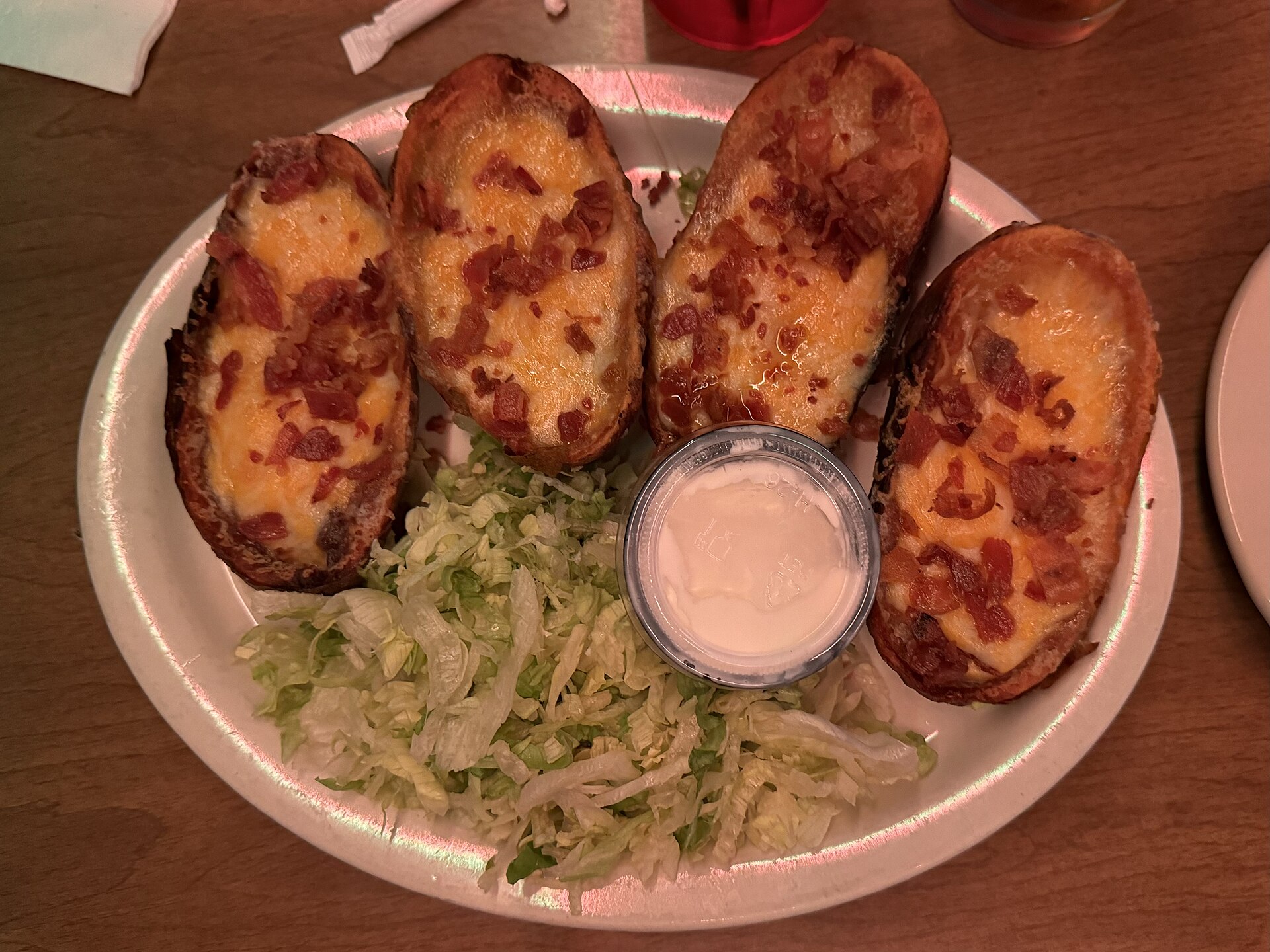 Cheesy potato skins topped with bacon, served with sour cream