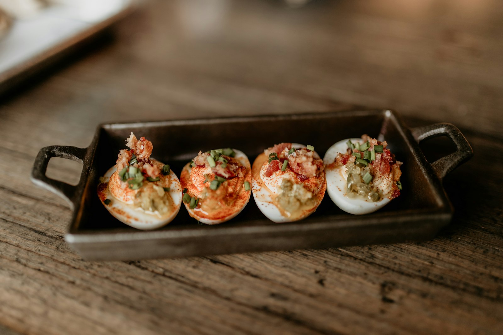 Deviled eggs topped with pimento and green onion in a small tray
