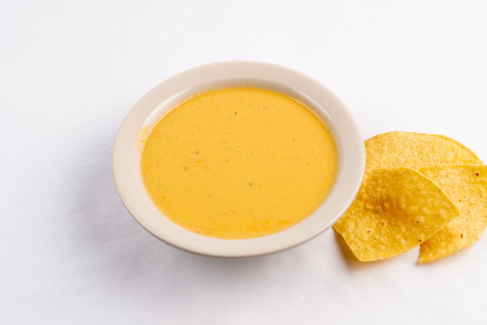 Bowl of homemade nacho cheese sauce with chips