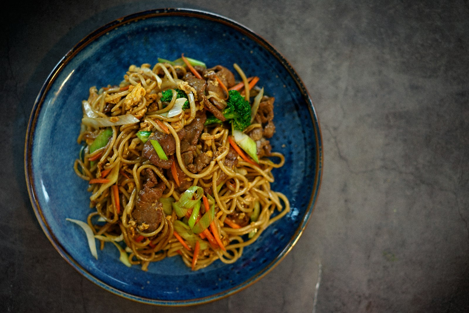 Stir fried noodles with beef in a blue bowl