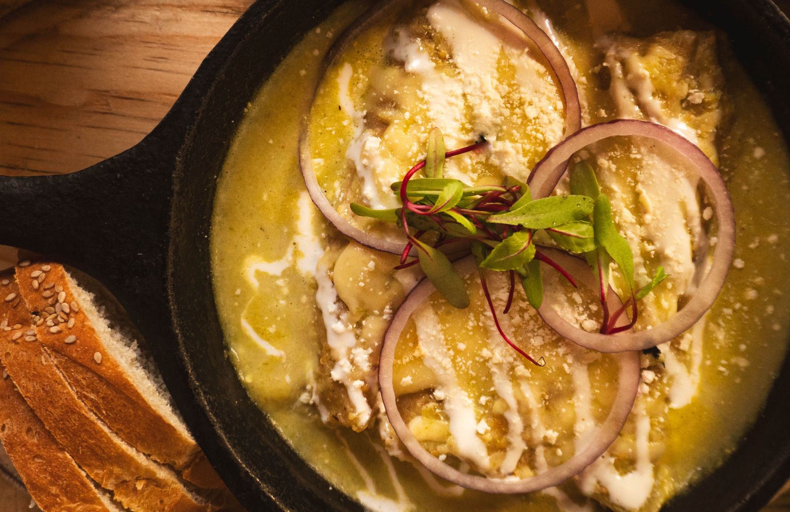 Pan of creamy green chicken enchilada roll-ups with melted cheese