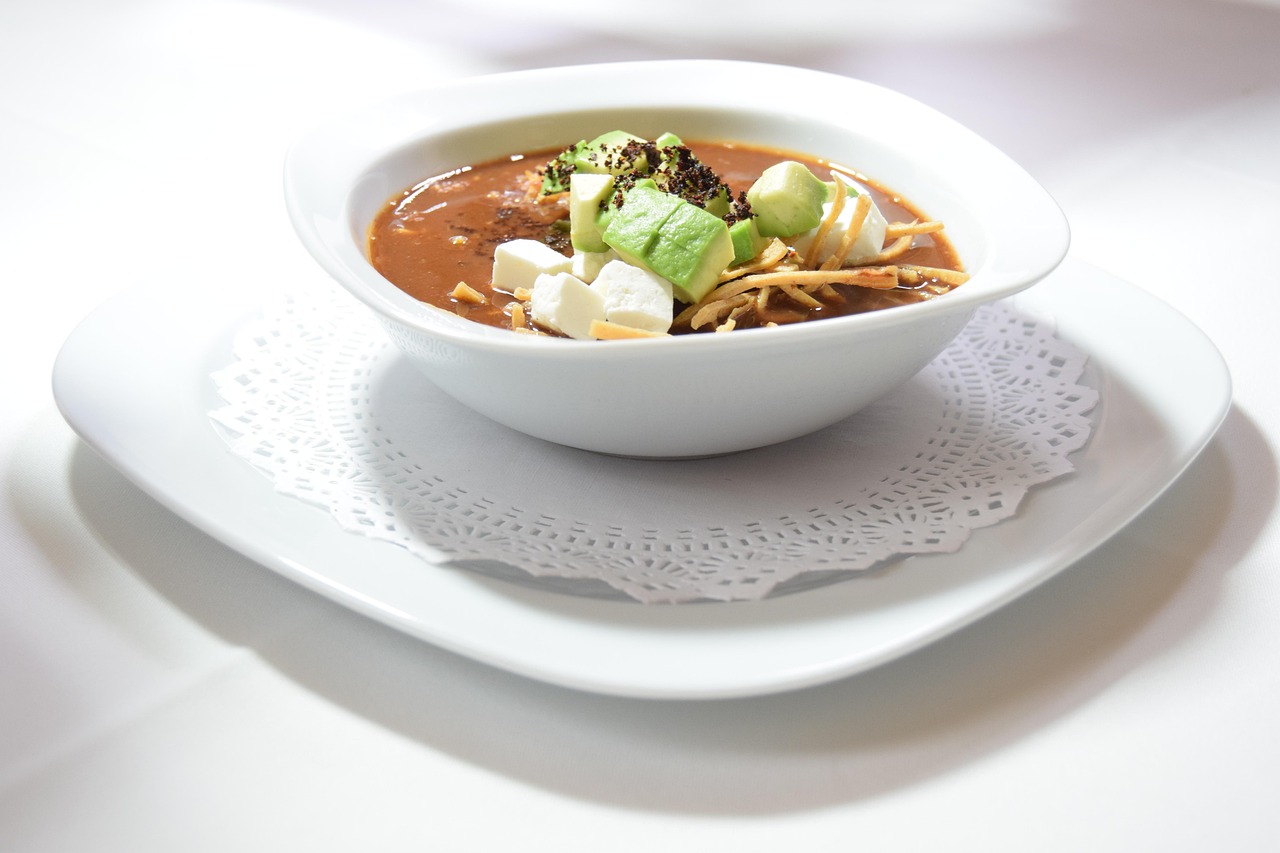Bowl of chicken tortilla soup topped with crispy strips and avocado