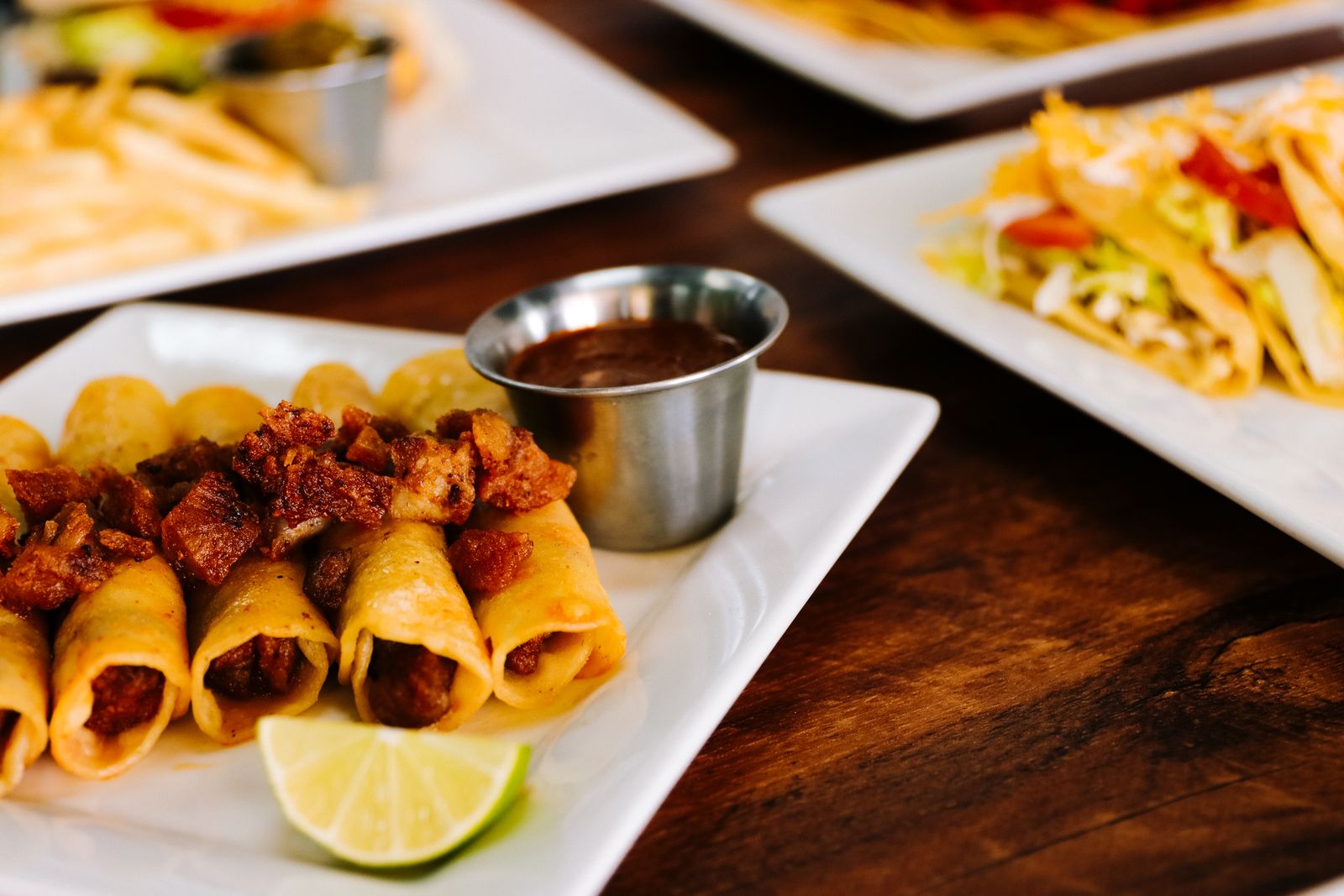 Golden chicken taquitos on a sheet pan with guacamole