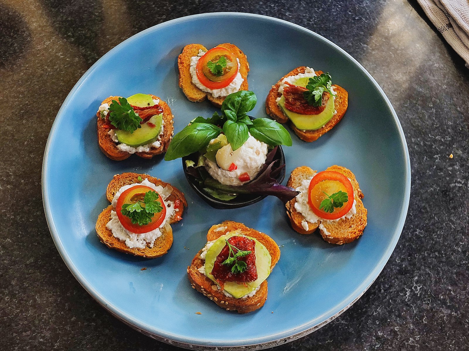 Mini crostini topped with roasted vegetables on a blue plate