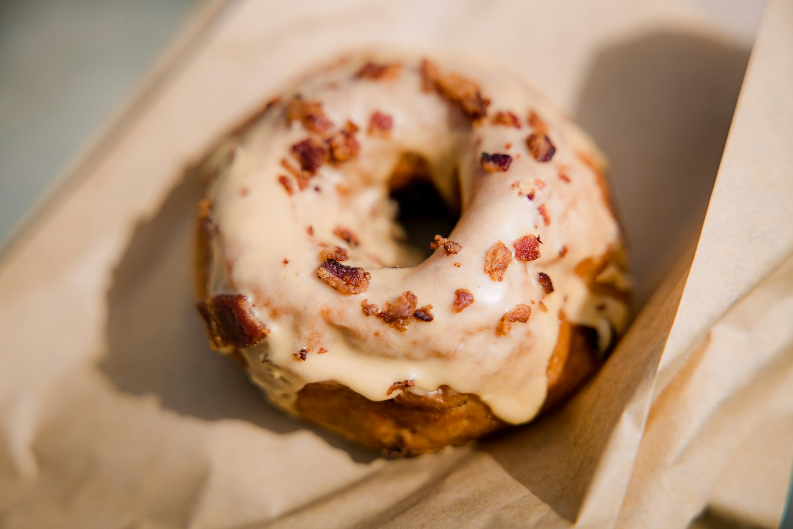 A glazed donut topped with bacon bits