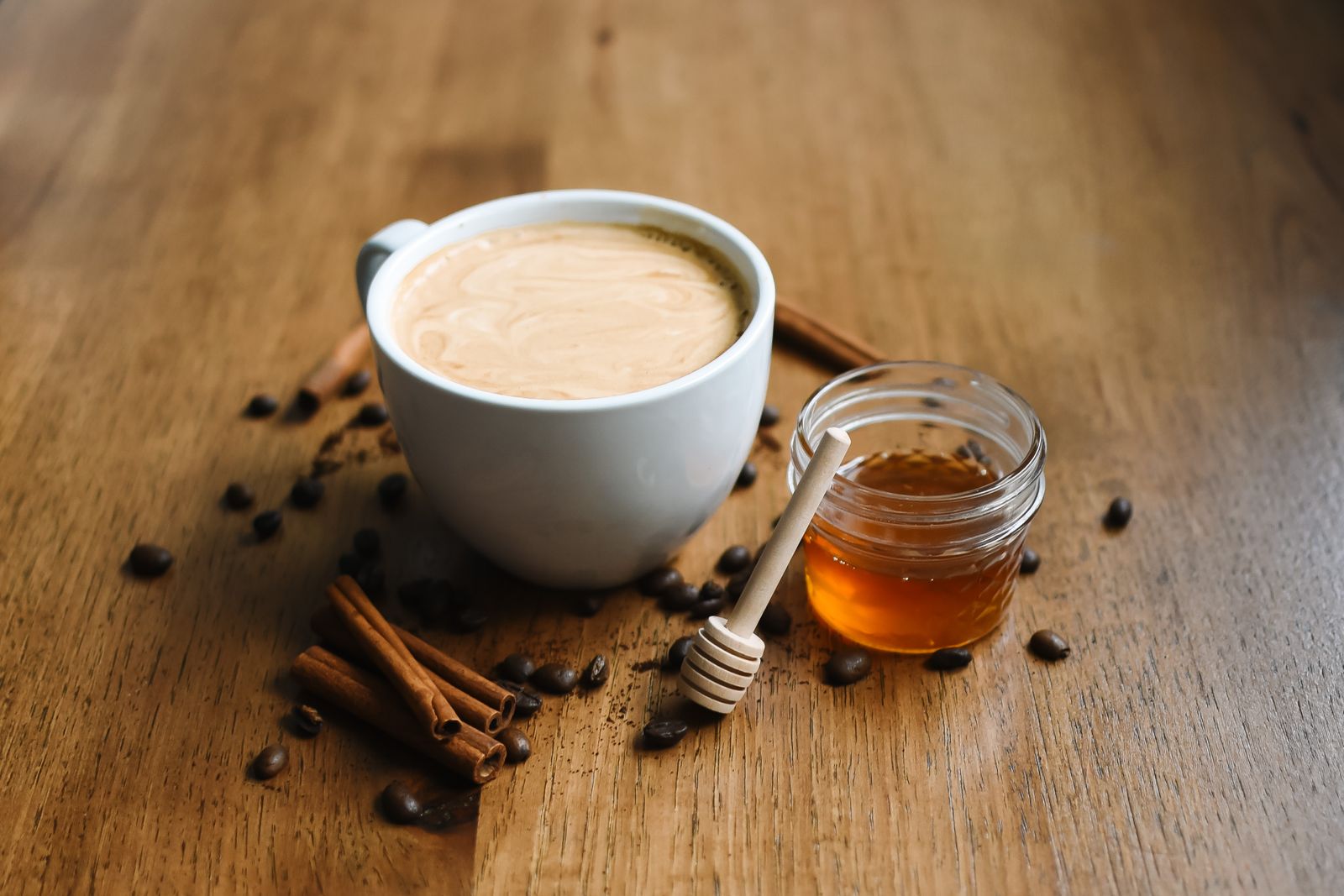 A cup of coffee with cinnamon sticks and honey, a lighter way to flavor coffee without coffee creamer