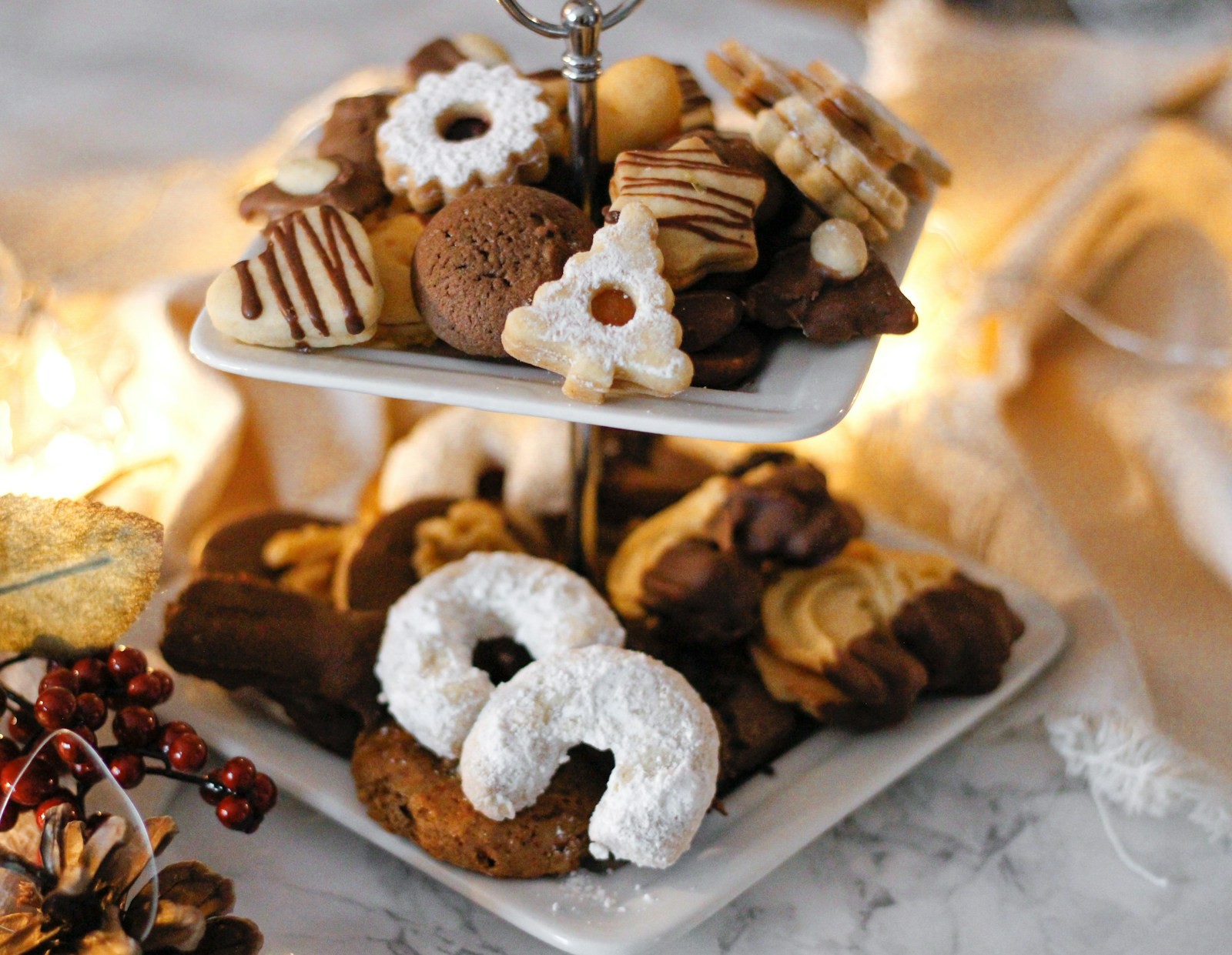 Two tier stand piled with Christmas cookies and powdered sugar crescents