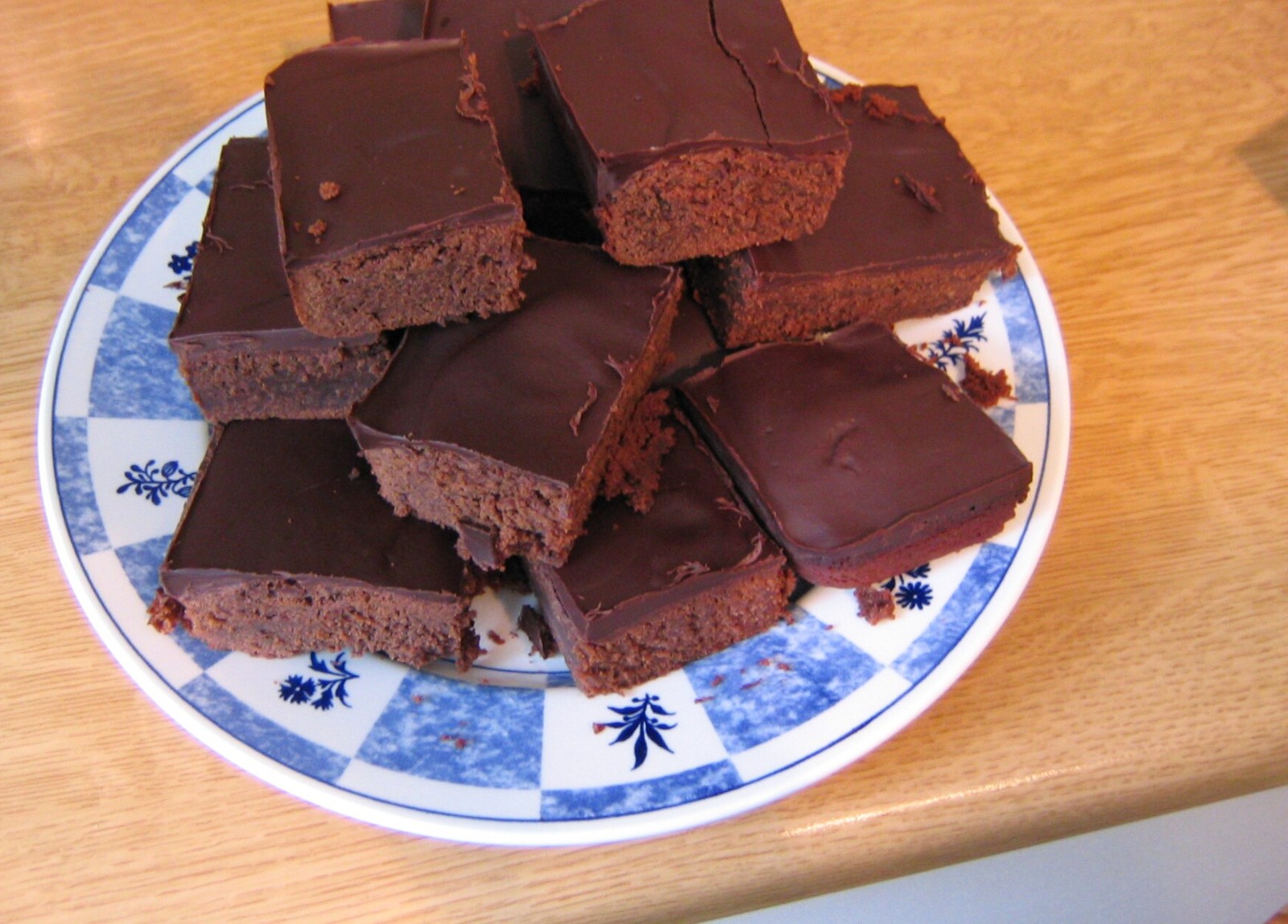 Cheap baking hacks: glazed chocolate brownie squares piled on a blue and white plate