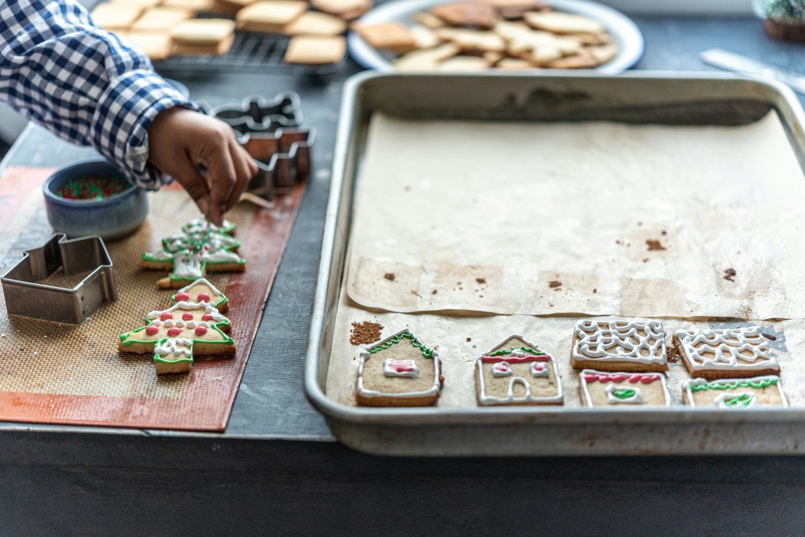 Decorating gingerbread house and tree cookies with icing on a silicone mat