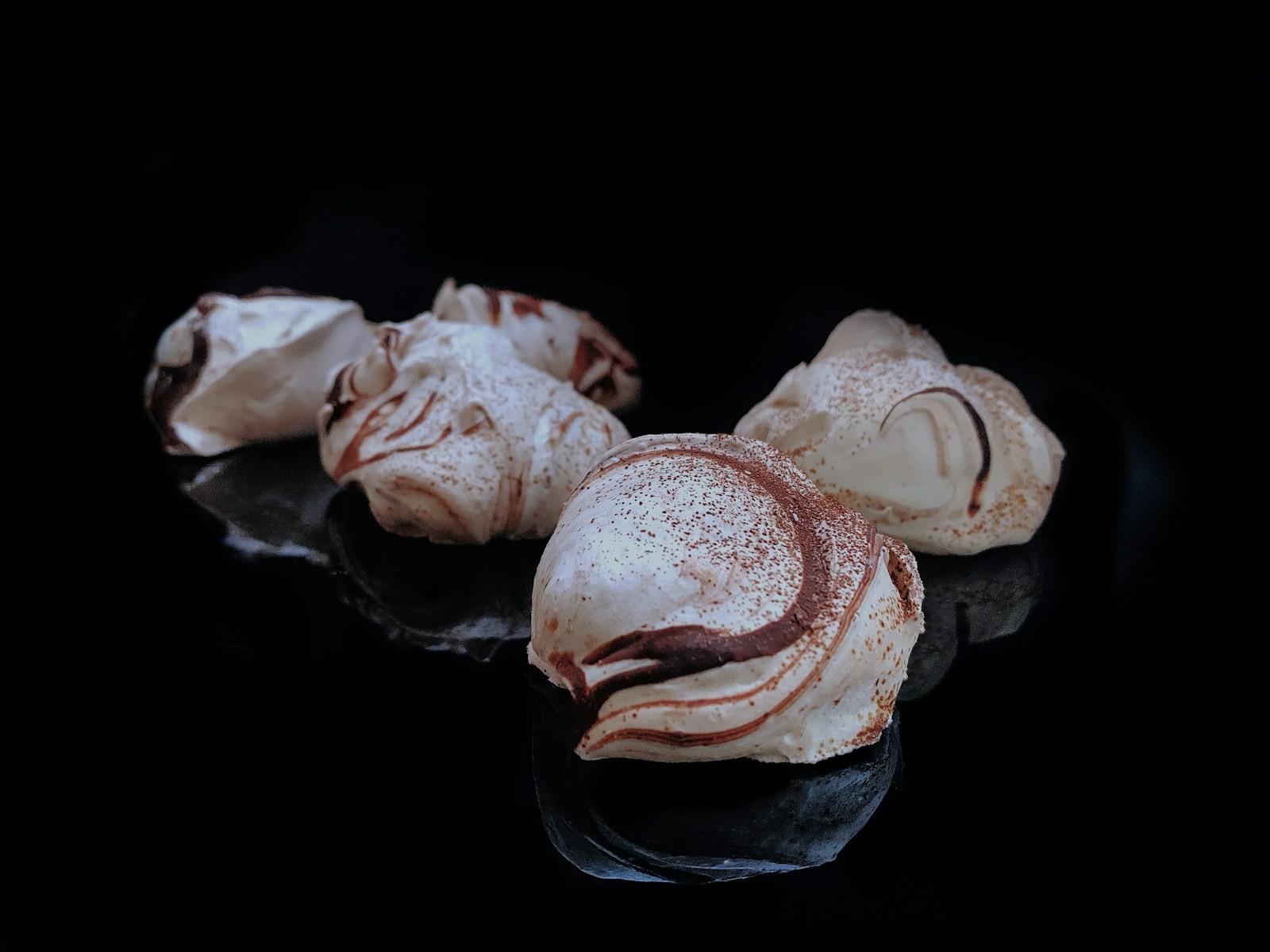 Chocolate swirl meringue cookies on a dark background