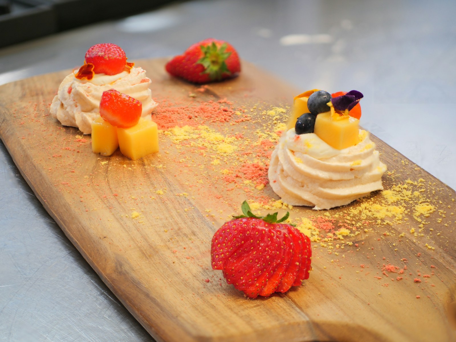 Mini pavlova nests with cream and strawberries on a wooden board