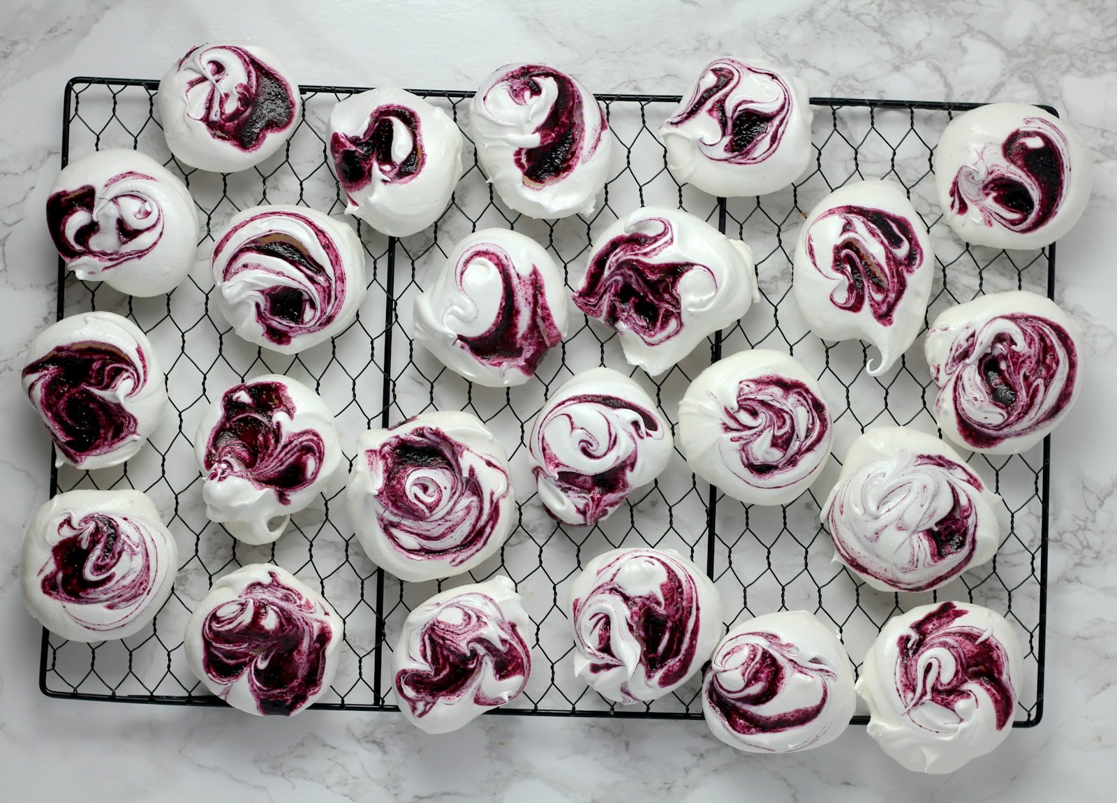 Raspberry swirl meringue kisses on a wire cooling rack
