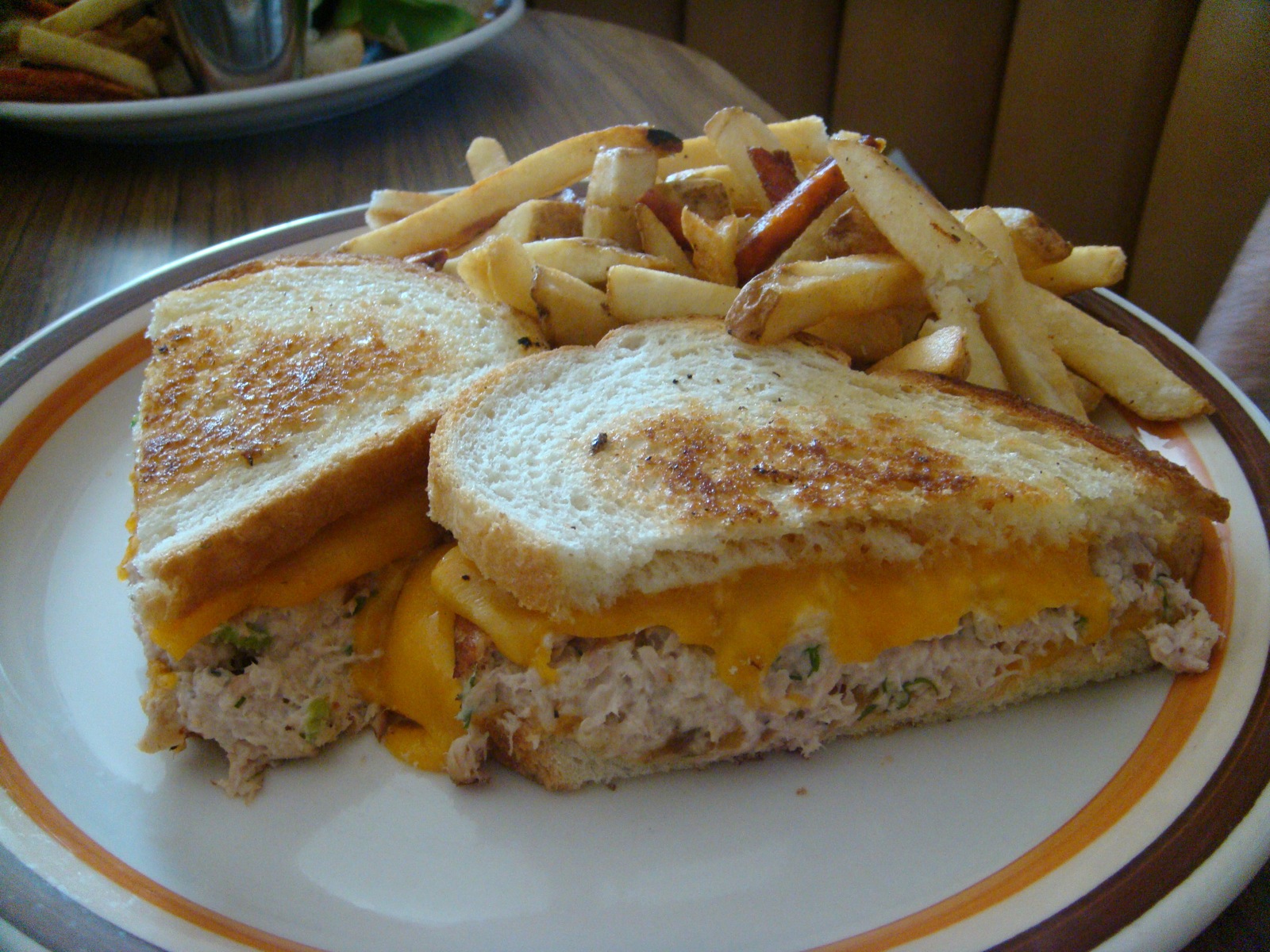 A toasted tuna melt sandwich with fries