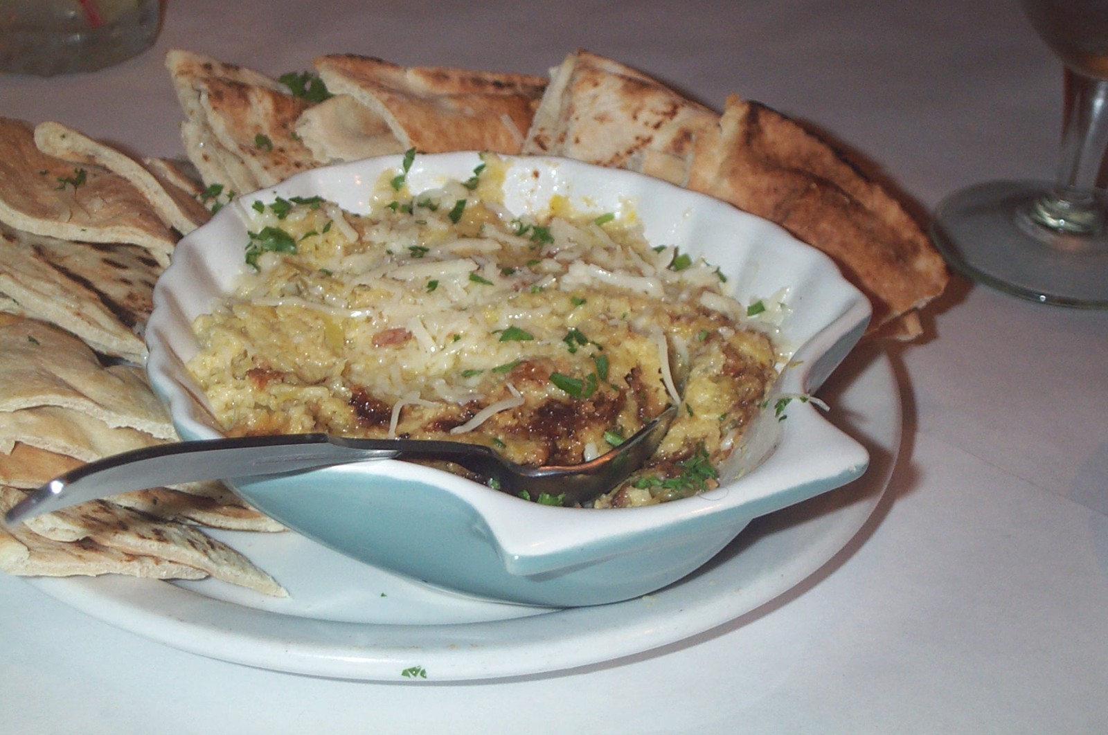 Hot artichoke dip in a shell-shaped dish with toasted pita