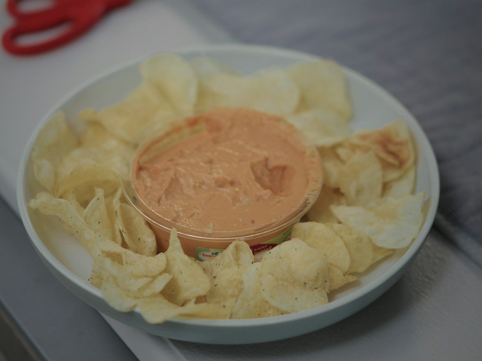 Creamy clam dip appetizer in a bowl surrounded by potato chips