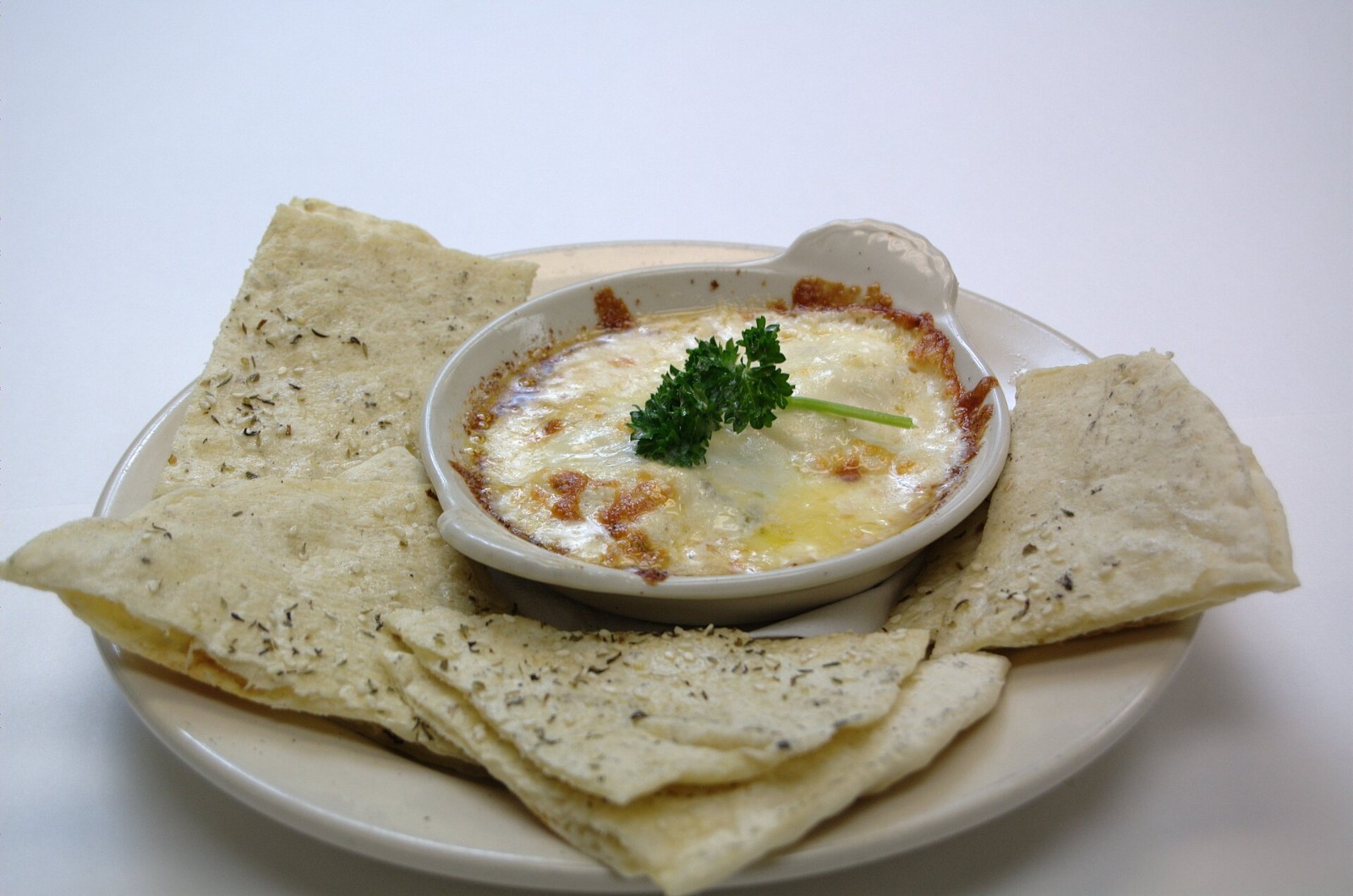 Warm crab dip in a small baking dish with flatbread wedges