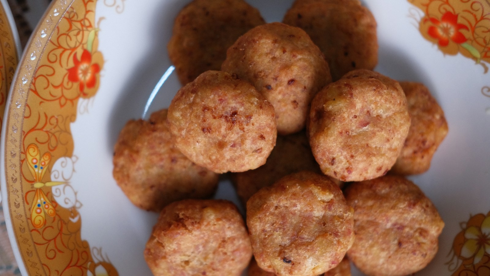 Golden sausage cheese balls piled on a vintage floral plate