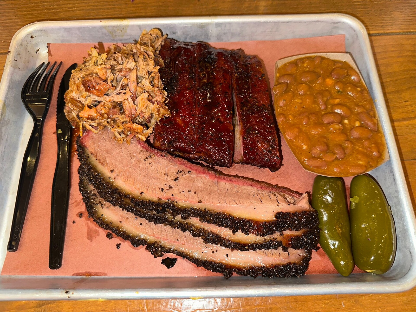 Texas barbecue plate with sliced brisket, ribs, pulled pork, beans and pickles