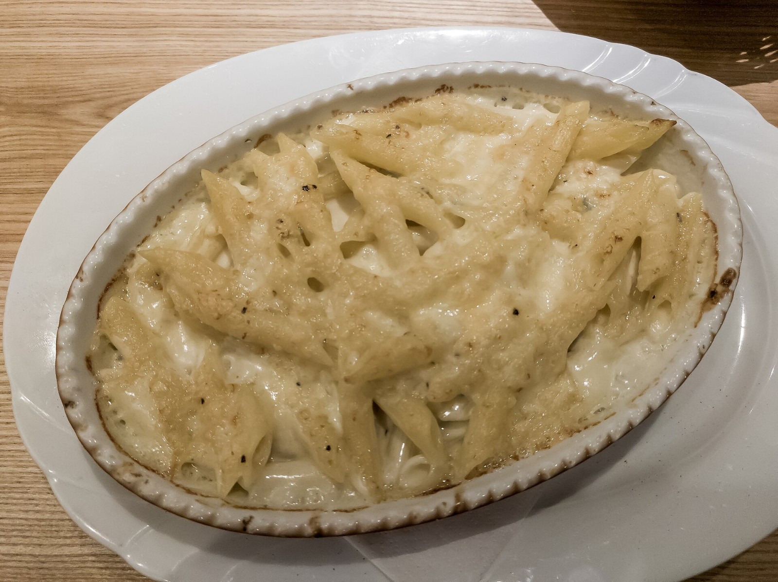 Creamy white Italian baked pasta with bechamel and parmesan crust in a round dish