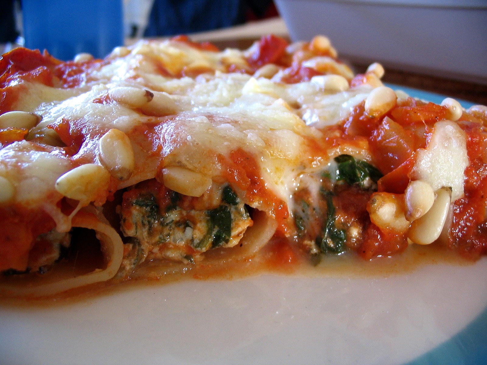 Stuffed manicotti tubes with spinach, ricotta, tomato sauce and pine nuts