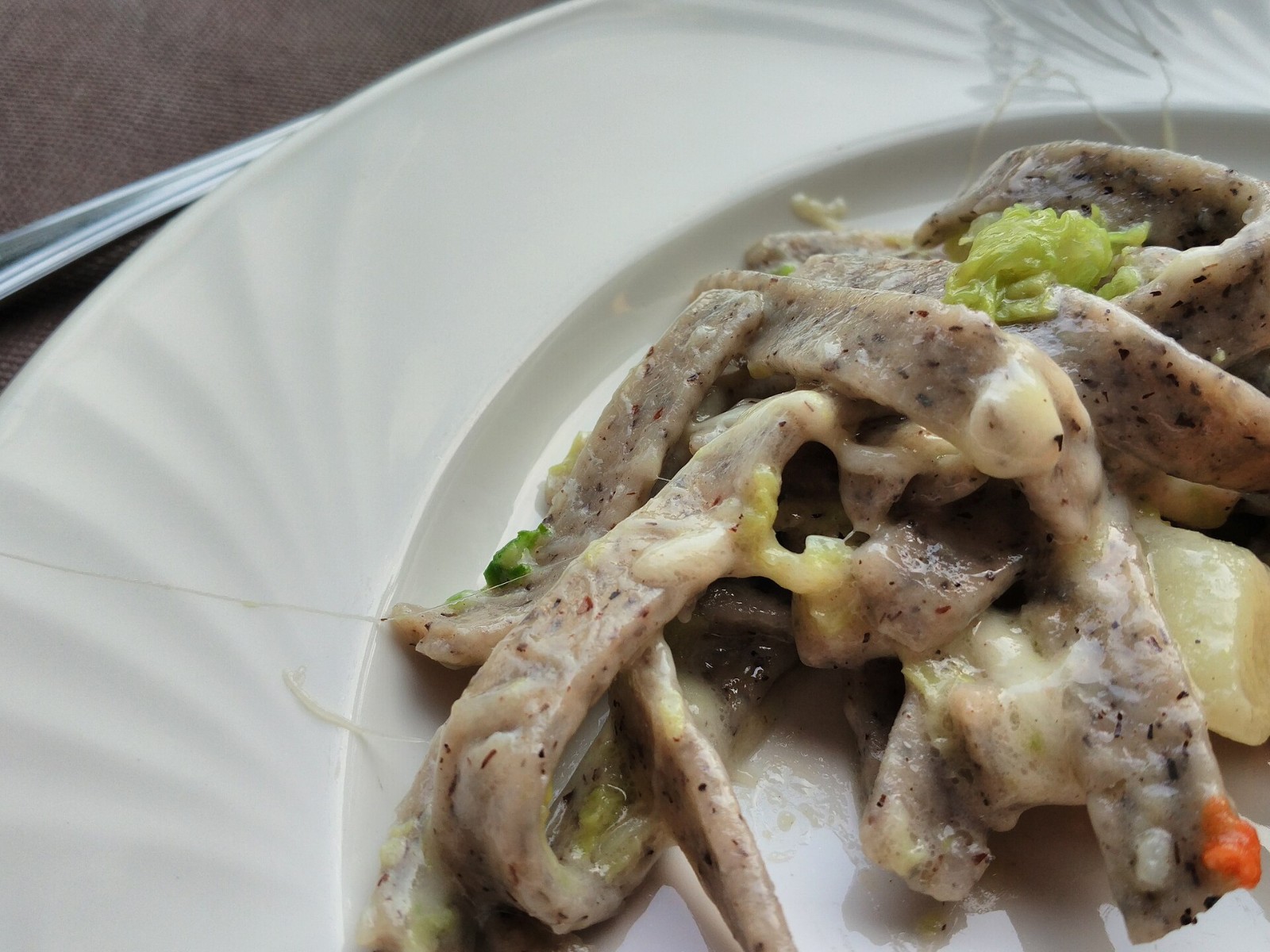 Buckwheat pizzoccheri noodles with potatoes, cabbage and melted cheese on a white plate