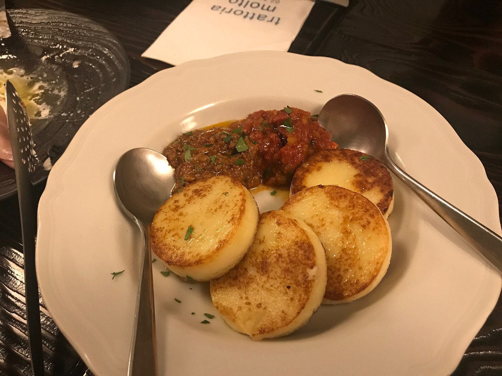 Golden semolina gnocchi rounds on a plate with tomato sauce