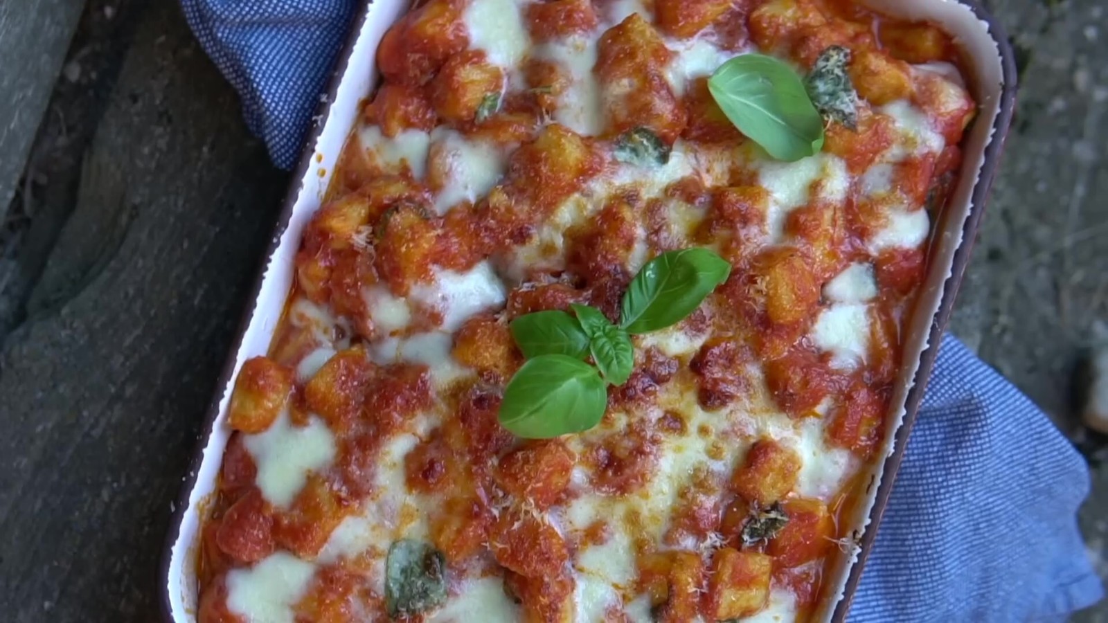 Potato gnocchi with tomato sauce, melted mozzarella and basil in a dish