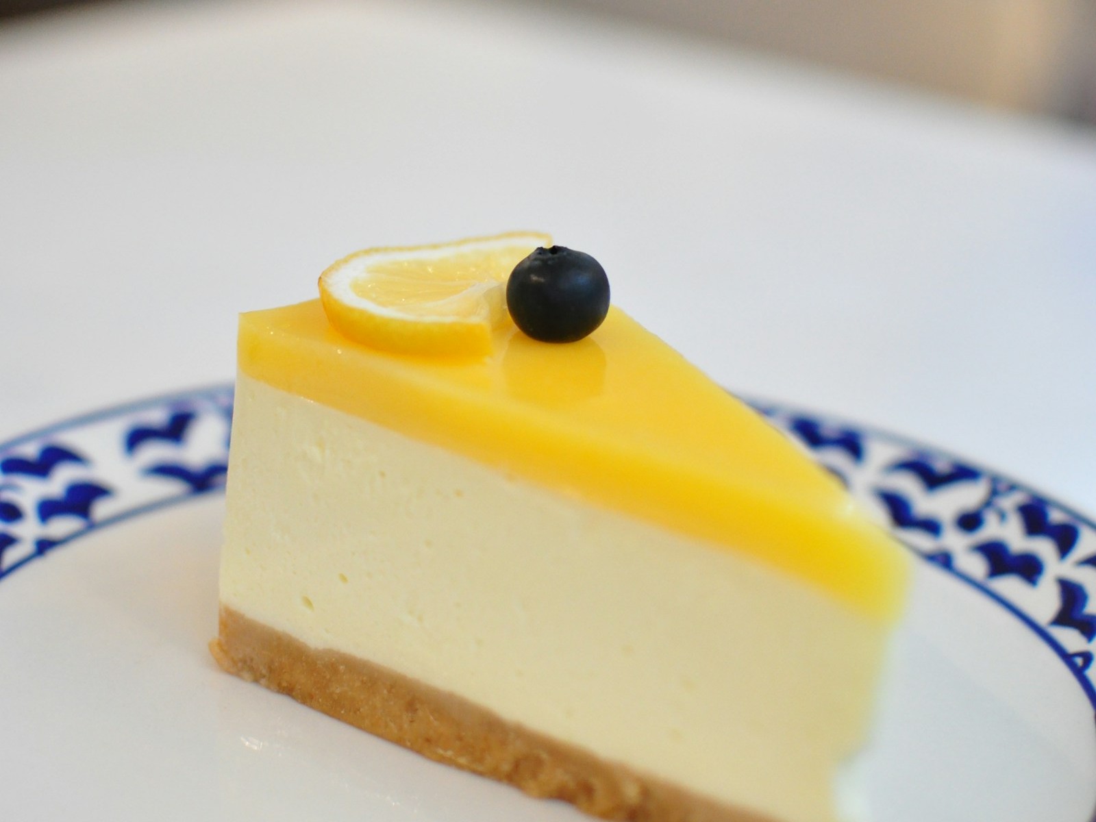 Wedge of creamy no-bake pie with a graham crust, a lemon slice and a blueberry on top