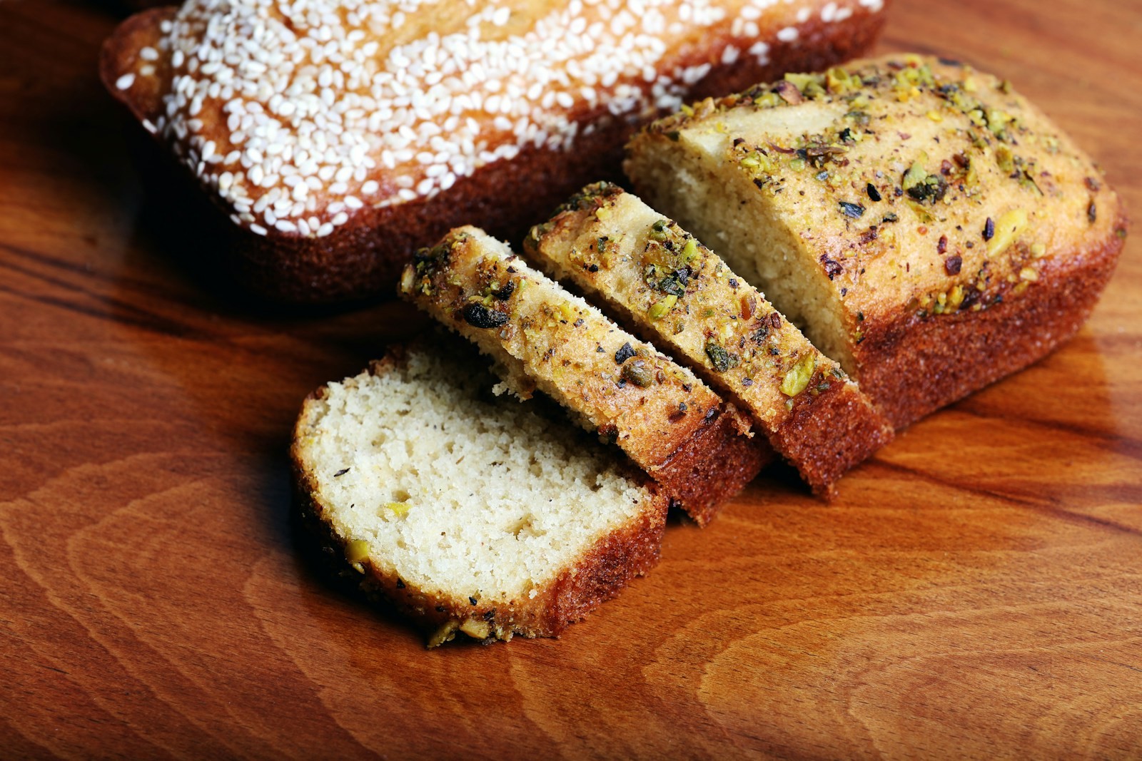 Sliced poppy seed loaf with a crackly sugar top on a wooden board