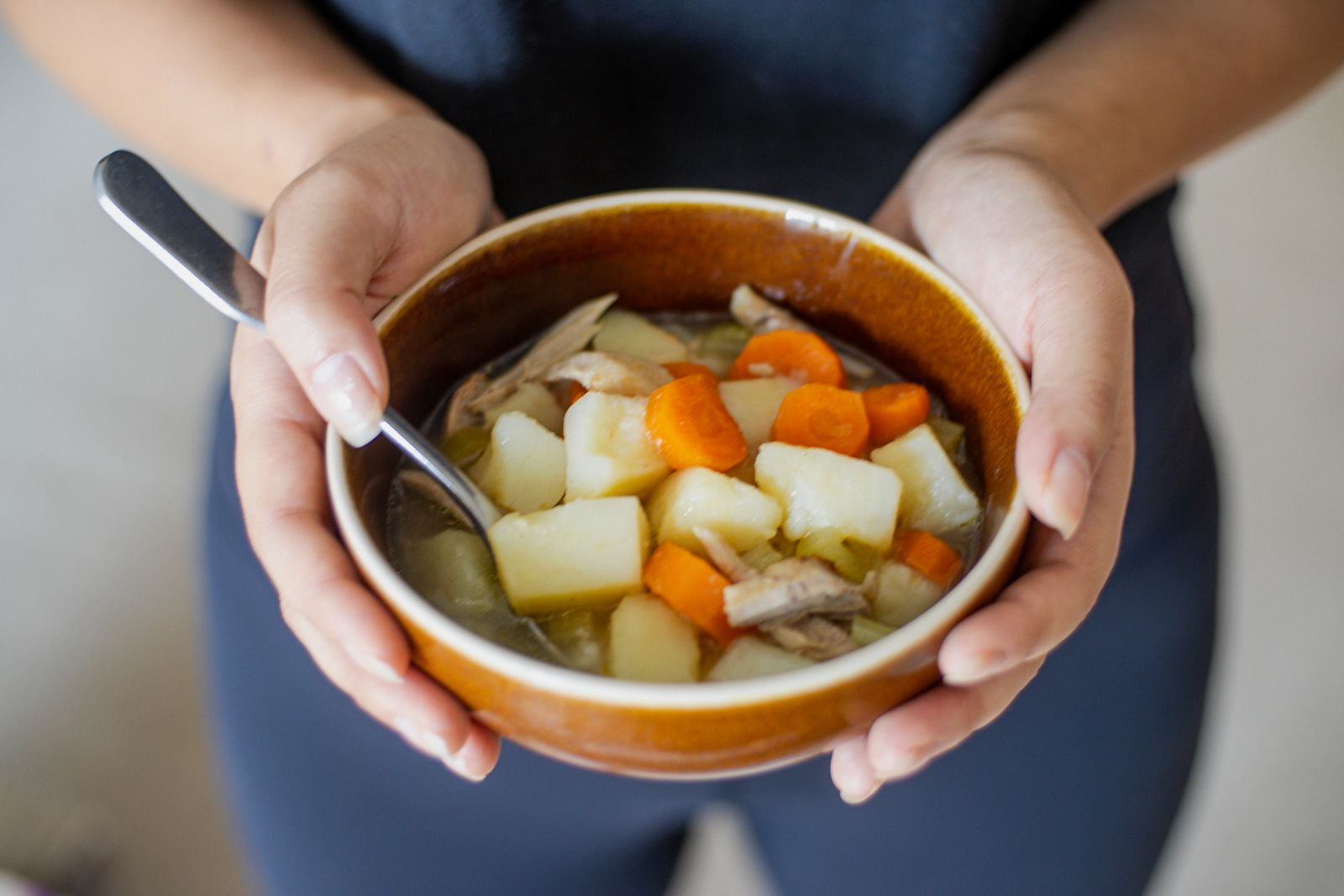 Chicken and vegetable bowl held in two hands