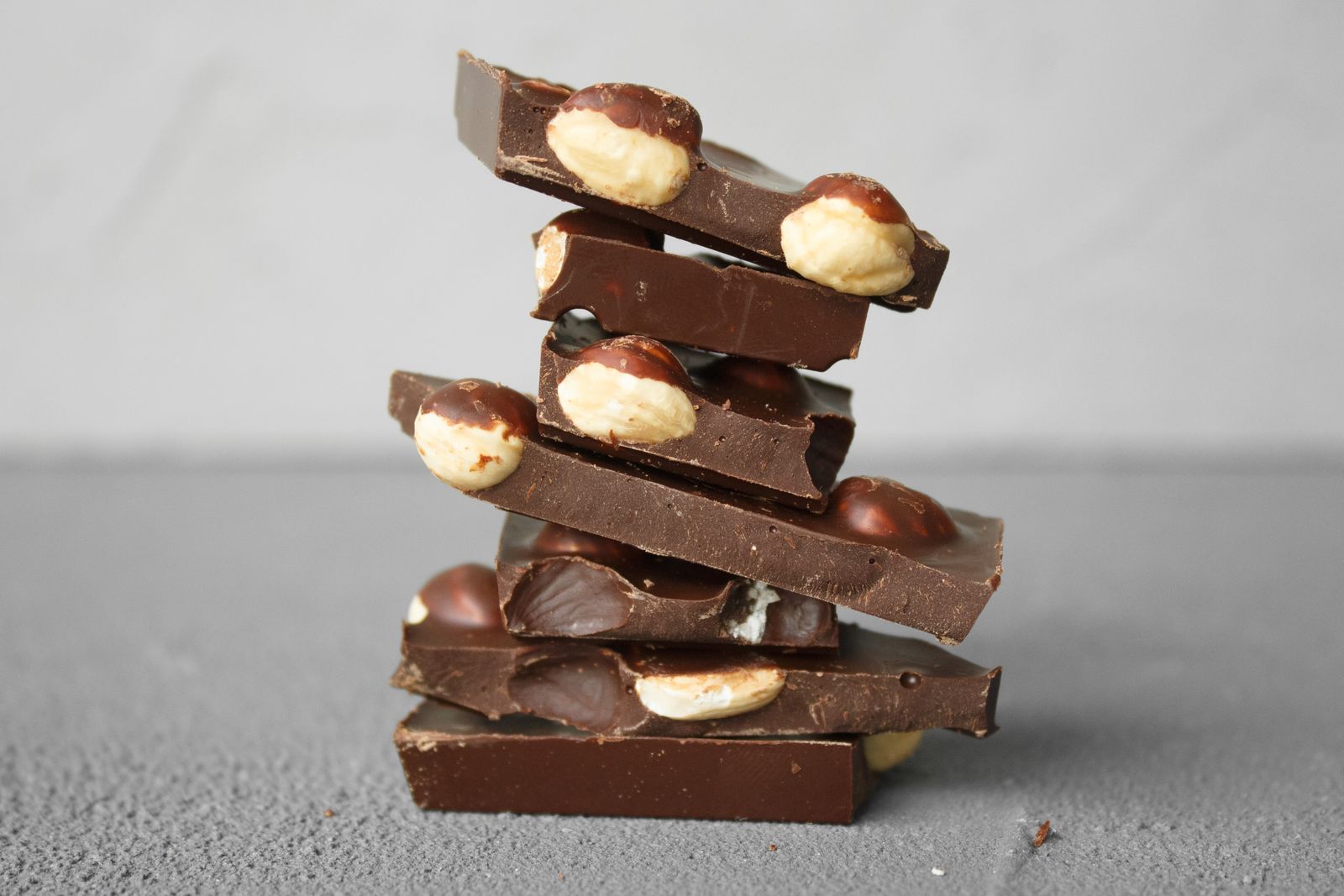 Stacked dark chocolate bars with whole nuts