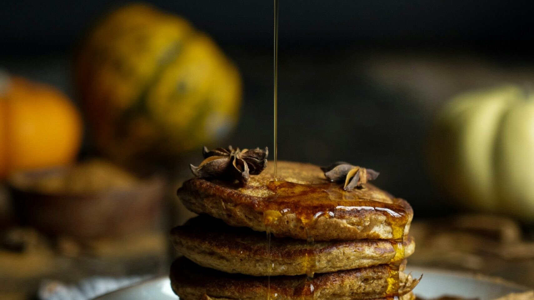 High-protein pumpkin recipes: a stack of pancakes with syrup being poured