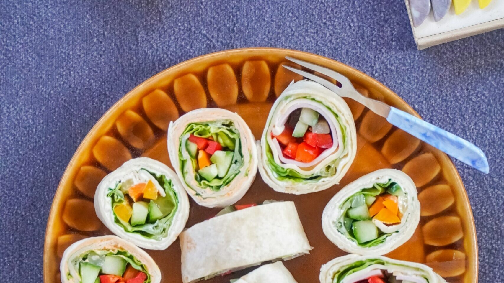 Colorful veggie tortilla rolls on a patterned plate