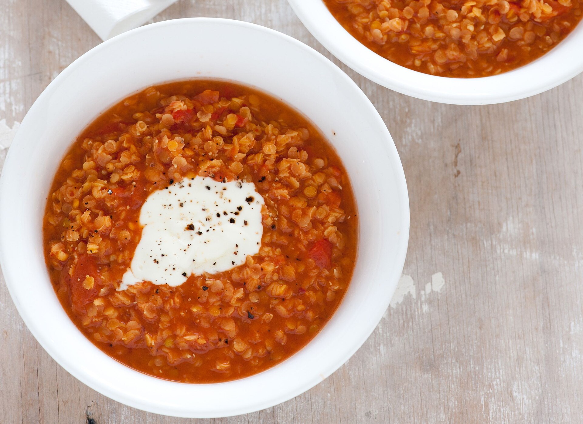 A bowl of red lentil soup with a swirl of yogurt