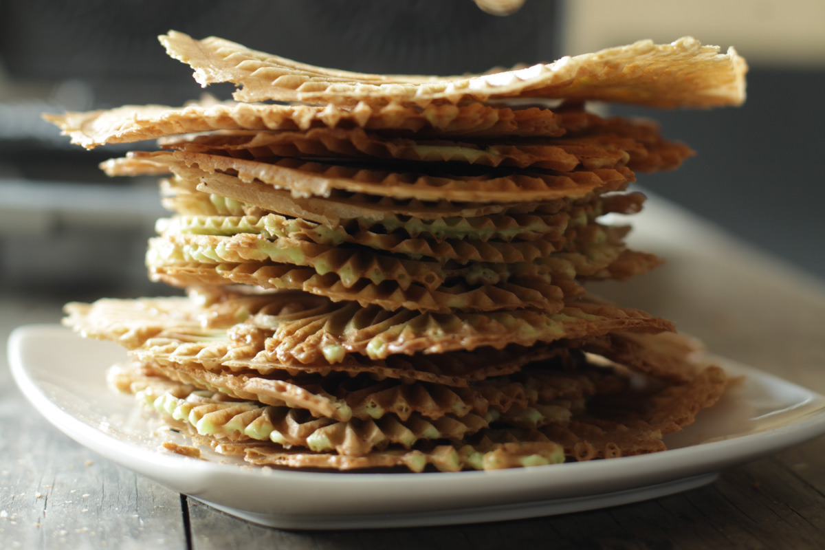 A stack of thin pizzelle cookies on a plate