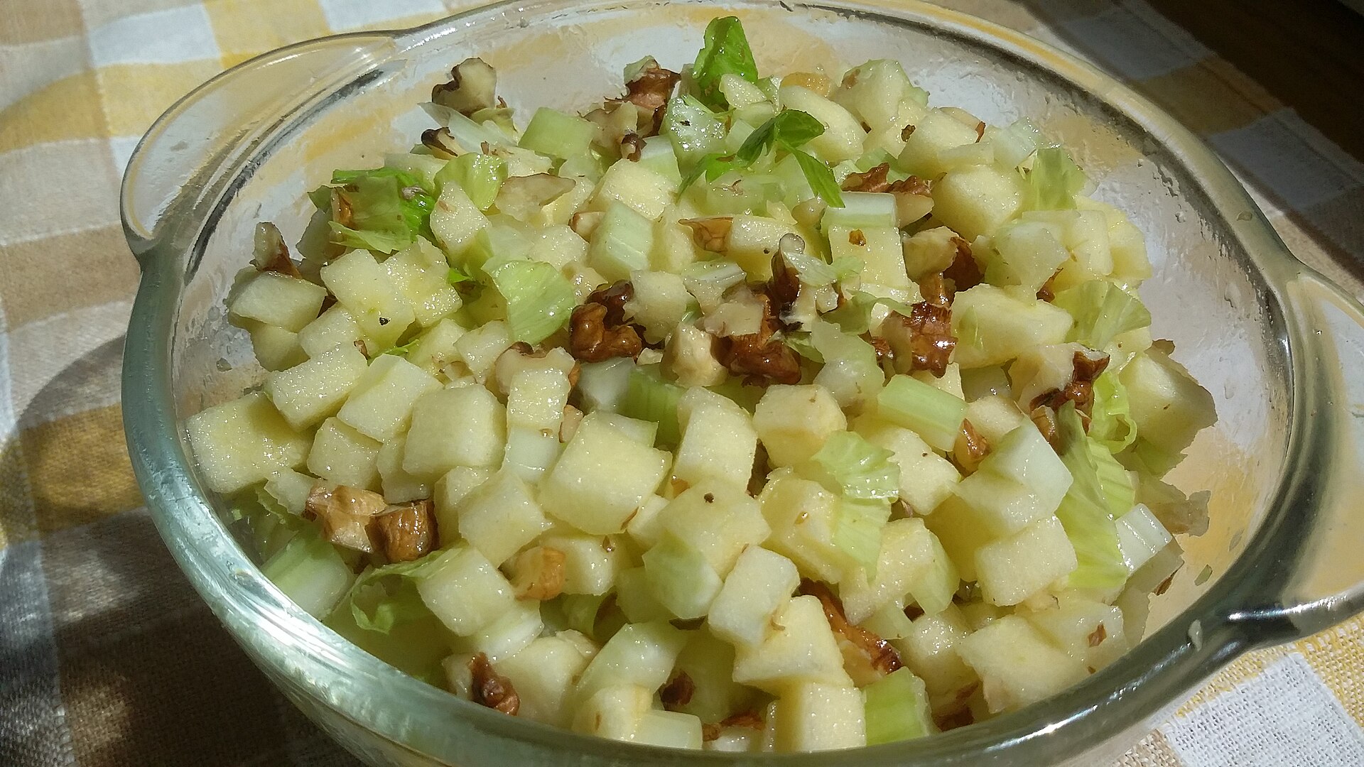 Waldorf salad with apples, celery and walnuts in a glass bowl